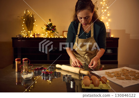 Woman Preparing Christmas Gingerbread Cookies in Festive Holiday Kitchen Woman Preparing Christmas Gingerbread Cookies in Festive Holiday Kitchen 130846122