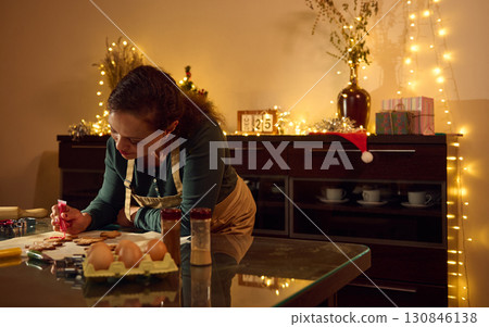 Woman Decorating Festive Gingerbread Cookies in Warm Christmas Kitchen Setting Woman Decorating Festive Gingerbread Cookies in Warm Christmas Kitchen Setting 130846138