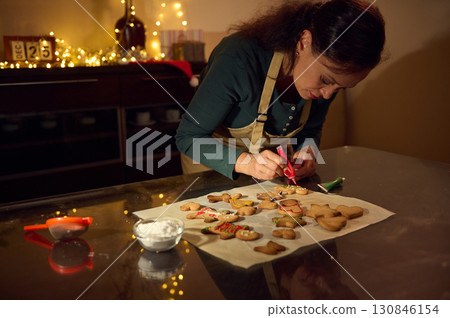 Woman Decorating Gingerbread Cookies in a Festive Christmas Setting Woman Decorating Gingerbread Cookies in a Festive Christmas Setting 130846154