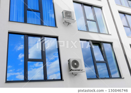 Condenser unit or compressor outside of residential building. Unit of central air conditioner AC or heating ventilation air conditioning system HVAC. Electric fan AC hangs on the wall 130846746