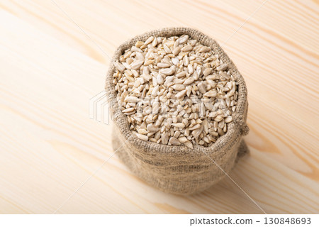 Peeled sunflower grain in small linen sack. Fresh harvested sunflower seeds on wooden table Peeled sunflower grain in small linen sack. Fresh harvested sunflower seeds on wooden table 130848693
