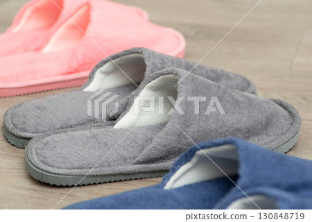 Three pairs of slippers on the floor. Colourful home footwear on the floor 130848719