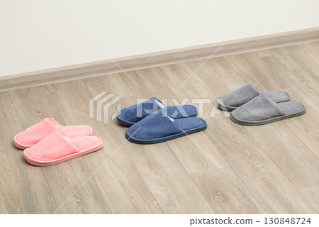 Concept of queue. Three pairs of slippers one by one on wooden floor 130848724