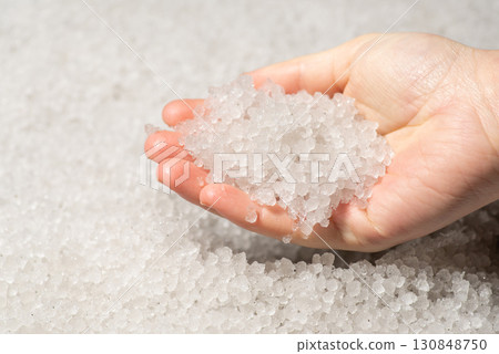 Hail in hands of a woman. Ground completely covered in ice hail Hail in hands of a woman. Ground completely covered in ice hail 130848750