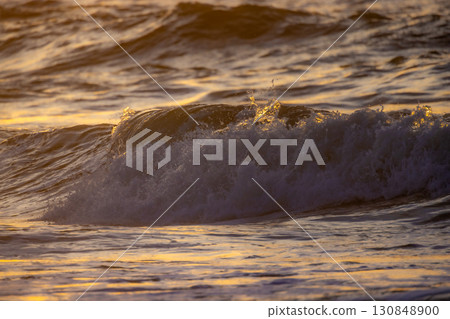 Golden Waves Gently Dancing at Sunset Over the Tranquil and Vast Ocean Waters Around Us Golden Waves Gently Dancing at Sunset Over the Tranquil and Vast Ocean Waters Around Us 130848900