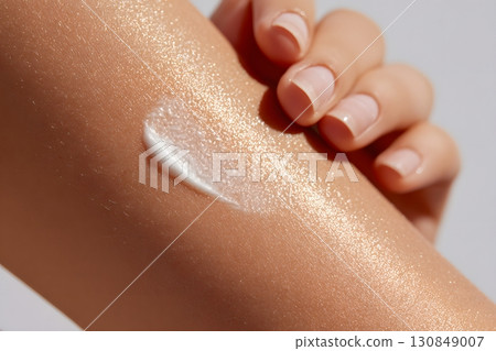 A rich white cream is gently applied on smooth, shimmering skin, revealing deep hydration and a beautiful, healthy glow. 130849007