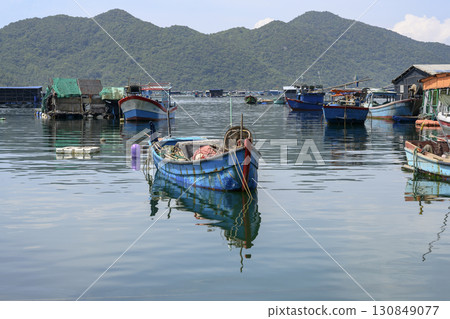 Fishing village with fishing boats and sheds in the sea bay near the mountains in Vietnam Fishing village with fishing boats and sheds in the sea bay near the mountains in Vietnam 130849077