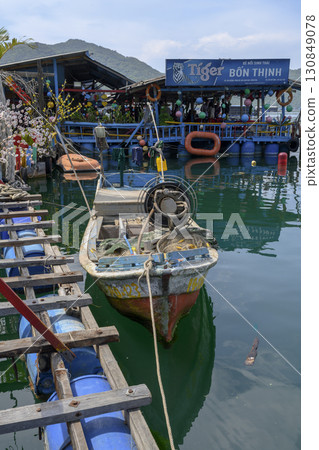 Fishing boat near the pier in the sea bay next to a village cafe Fishing boat near the pier in the sea bay next to a village cafe 130849078