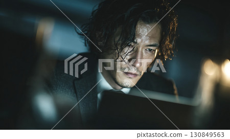 A businessman concentrating while sweating in the office at night A businessman concentrating while sweating in the office at night 130849563