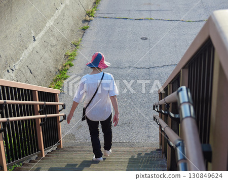 A woman descending the stairs of a seaside embankment on a summer evening 130849624
