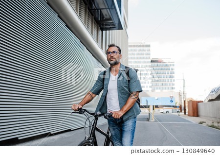 City commuter riding bike on street, wearing backpack. 130849640