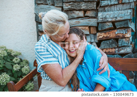 Grandmother and granddaughter hugging in the garden. Grandmother and granddaughter hugging in the garden. 130849673