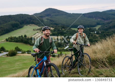 Couple cycling together in nature, smiling and enjoying outdoor adventure. 130849731