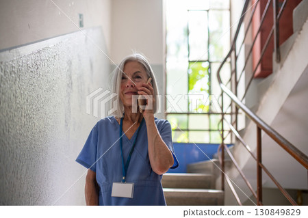 Tired nurse taking break during hospital shift, calling with family. 130849829