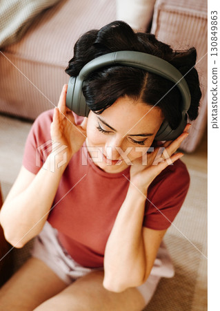 Woman relaxing at home with hair rollers and headphones 130849863