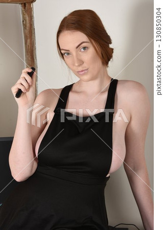 Tall, shapely, redhead model dressed as a sexy secretary in her office in an old building 130850304