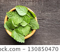 Fresh green organic mint leaves on wooden table closeup. Selective focus. Peppermint in a bowl on natural wooden background 130850470