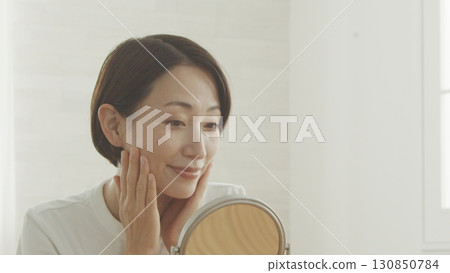 中年婦女對著鏡子檢查自己的皮膚狀況 130850784