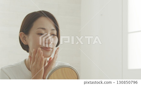 Middle-aged woman checking her skin condition in the mirror 130850796