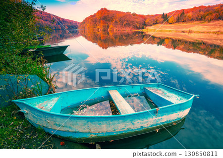 Lakeshore with boat in autumn. View of the lake with reflection 130850811