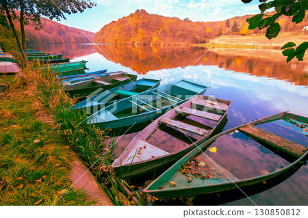 Lakeshore with boats in autumn. View of the lake with reflection Lakeshore with boats in autumn. View of the lake with reflection 130850812