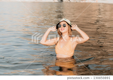 Woman Beach Water Sunglasses - Happy woman in a swimsuit and sunglasses standing in the water on a beach. Woman Beach Water Sunglasses - Happy woman in a swimsuit and sunglasses standing in the water on a beach. 130850891