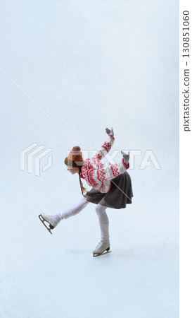 Figure skater in festive outfit stretching in dynamic winter performance 130851060