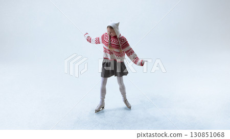 Young skater in cozy red patterned sweater gliding playfully on ice Young skater in cozy red patterned sweater gliding playfully on ice 130851068