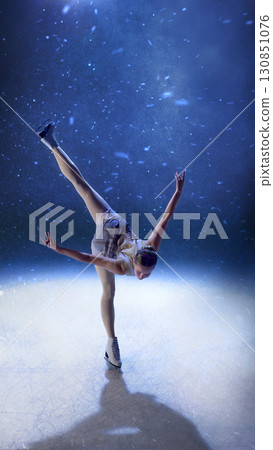 Female skater bending forward in powerful spin with extended leg on ice 130851076