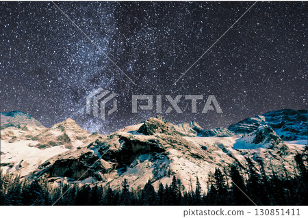 night view of snowy mountain range and milky way. starry night sky with stars and moon. beautiful landscape with snowy mountain peaks in winter night. 130851411