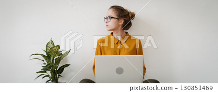 Young female student studying, working on laptop. 130851469