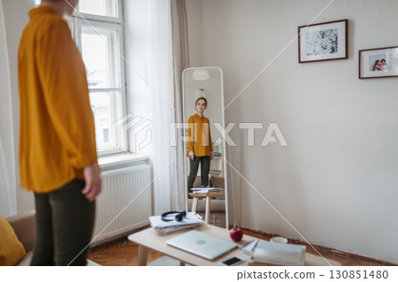 Depressed woman looking at herself in mirror. 130851480