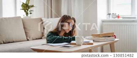 Young female student sitting on floor and studying. 130851482
