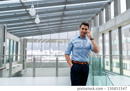 Young businessman making phone call indoors in an office. Young businessman making phone call indoors in an office. 130851547