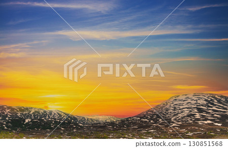 Mountain landscape with peaks covered with melted snow. Aerial view of snow covered mountains in summer during sunset 130851568