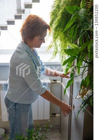 Woman opening a metal safe with stored documents in an office environment. Paperwork security, archive access, and administrative responsibility. 130852200