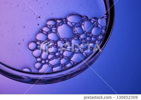 The texture of a cosmetic serum with a trail of bubbles on a purple background. The texture of a cosmetic serum with a trail of bubbles on a purple background. 130852309