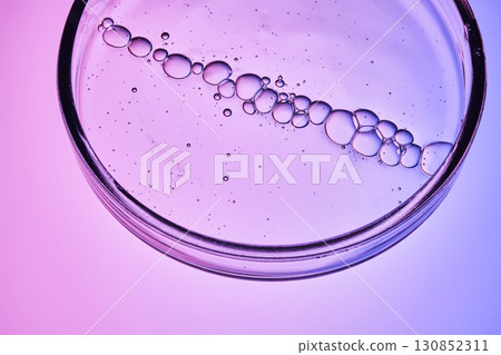 The texture of a cosmetic serum with a trail of bubbles on a purple background. 130852311