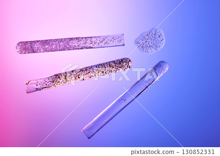 Textures of cosmetic serums in test tubes on a blue-purple background. 130852331