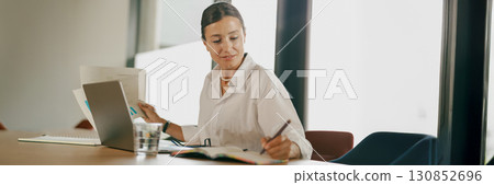 A Focused and Professional Woman Engaged in Tasks in a Modern Office Environment A Focused and Professional Woman Engaged in Tasks in a Modern Office Environment 130852696