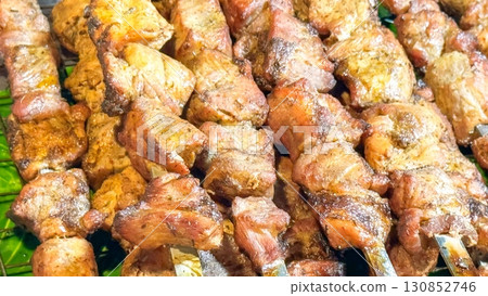 Sizzling skewers of marinated meat showcase the essence of street food, each piece glistening with spices, inviting a flavorful experience of wild feasting and open-air dining Sizzling skewers of marinated meat showcase the essence of street food, each piece glistening with spices, inviting a flavorful experience of wild feasting and open-air dining 130852746