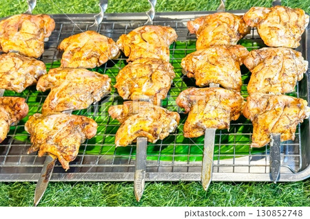 Grilled chicken skewers rest on a grill, the charred lines marking their juicy perfection, an inviting sight for those seeking the simple pleasures of street food and the rustic charm of wild feasting Grilled chicken skewers rest on a grill, the charred lines marking their juicy perfection, an inviting sight for those seeking the simple pleasures of street food and the rustic charm of wild feasting 130852748