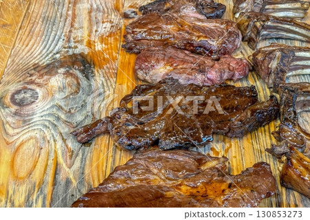Grilled steaks on a wooden board evoke rustic, outdoor cooking, promise a delicious taste experience, fitting for street food aficionados seeking authentic, hearty flavors 130853273