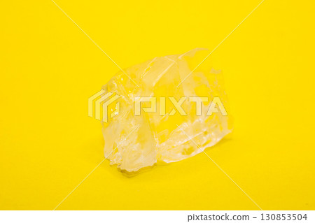 Large piece of crystal table salt on bright colored yellow background, close-up 130853504