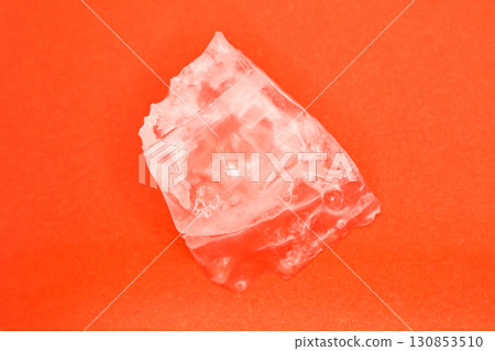 Large piece of crystal table salt on bright colored orange background, close-up Large piece of crystal table salt on bright colored orange background, close-up 130853510
