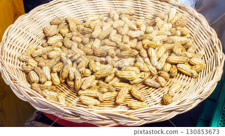 Wicker basket overflows with golden-brown roasted peanuts, wafting a smoky scent, epitomizing wholesome street fare and inviting nut aficionados to savor a classic, healthy crunchy treat Wicker basket overflows with golden-brown roasted peanuts, wafting a smoky scent, epitomizing wholesome street fare and inviting nut aficionados to savor a classic, healthy crunchy treat 130853673