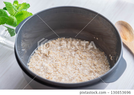 煮飯前將水和燕麥片放入耐熱容器中 煮飯前將水和燕麥片放入耐熱容器中 130853696