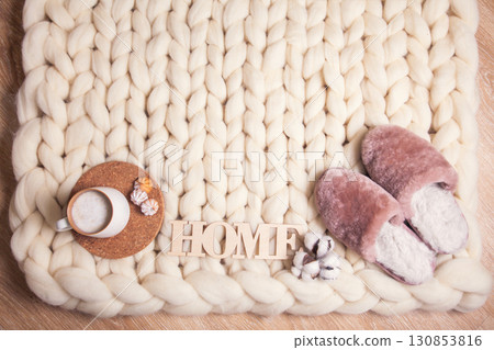 Home slippers made of fur, cup of cappuccino and inscription Home on blanket of thick yarn Home slippers made of fur, cup of cappuccino and inscription Home on blanket of thick yarn 130853816