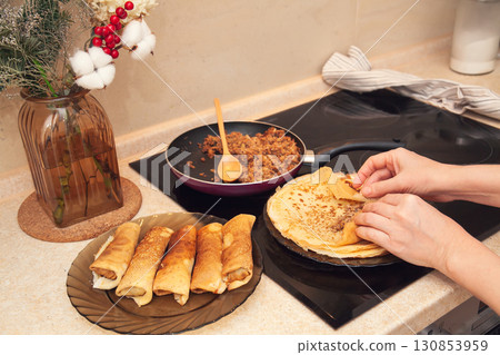Cooking homemade Russian pancakes Bliny with meat on Shrovetide - Maslenitsa. Woman cooks pancakes in her kitchen 130853959
