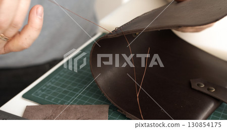 Sewing leather bag with strong thread and needle during artisan handmade crafting process 130854175